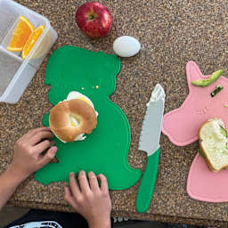 Handstand Kitchen Cutting Board & Knife Set, food on top of the Dinosaur cutting board.