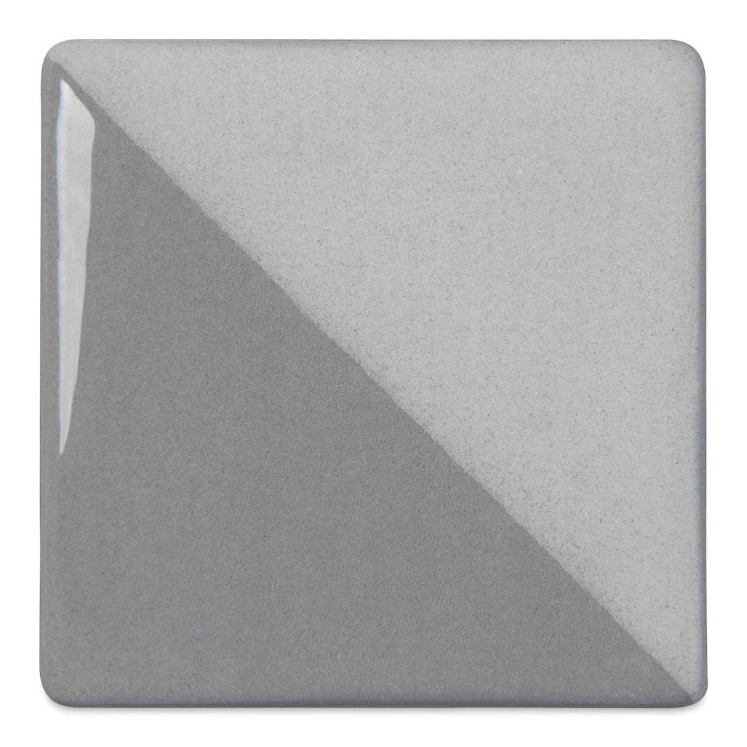 Open in modal - Speedball Ceramic Underglaze - Gray, Opaque, fired on white clay bisque tiles, half covered in Speedball Clear Glaze, fired to cone 05