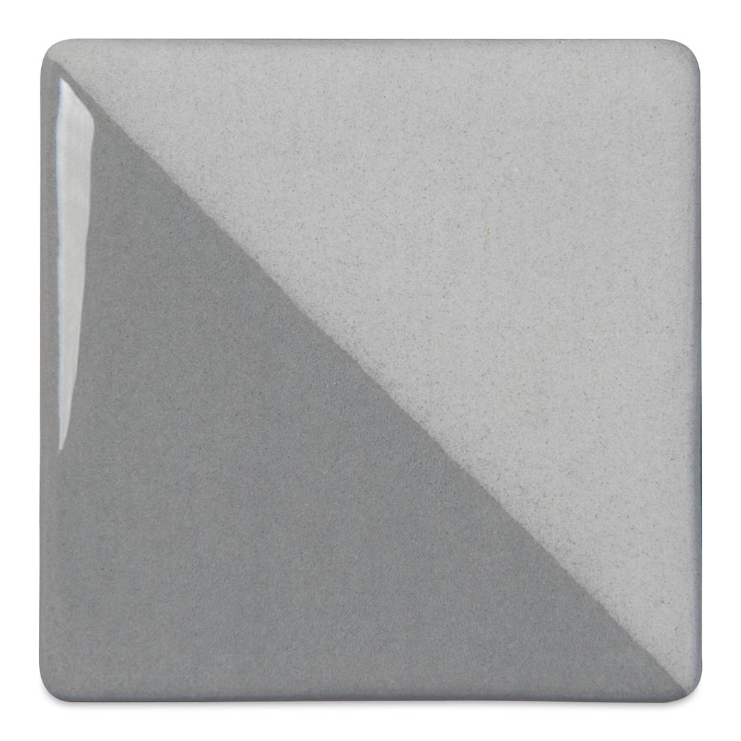 Open in modal - Speedball Ceramic Underglaze - Gray, Opaque, fired on white clay bisque tiles, half covered in Speedball Clear Glaze, fired to cone 05