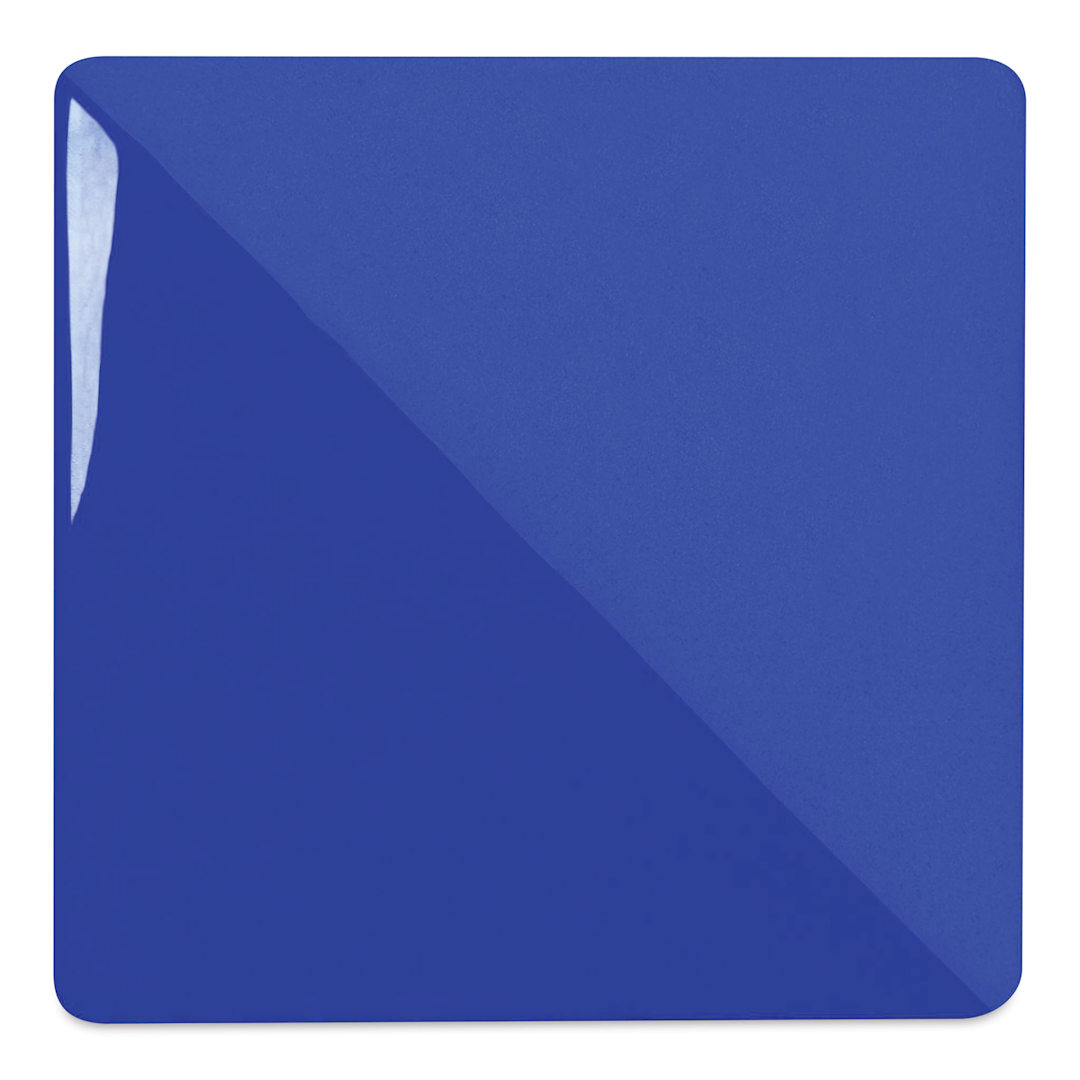 Open in modal - Speedball Ceramic Underglaze - Royal Blue, Opaque, fired on white clay bisque tiles, half covered in Speedball Clear Glaze, fired to cone 05