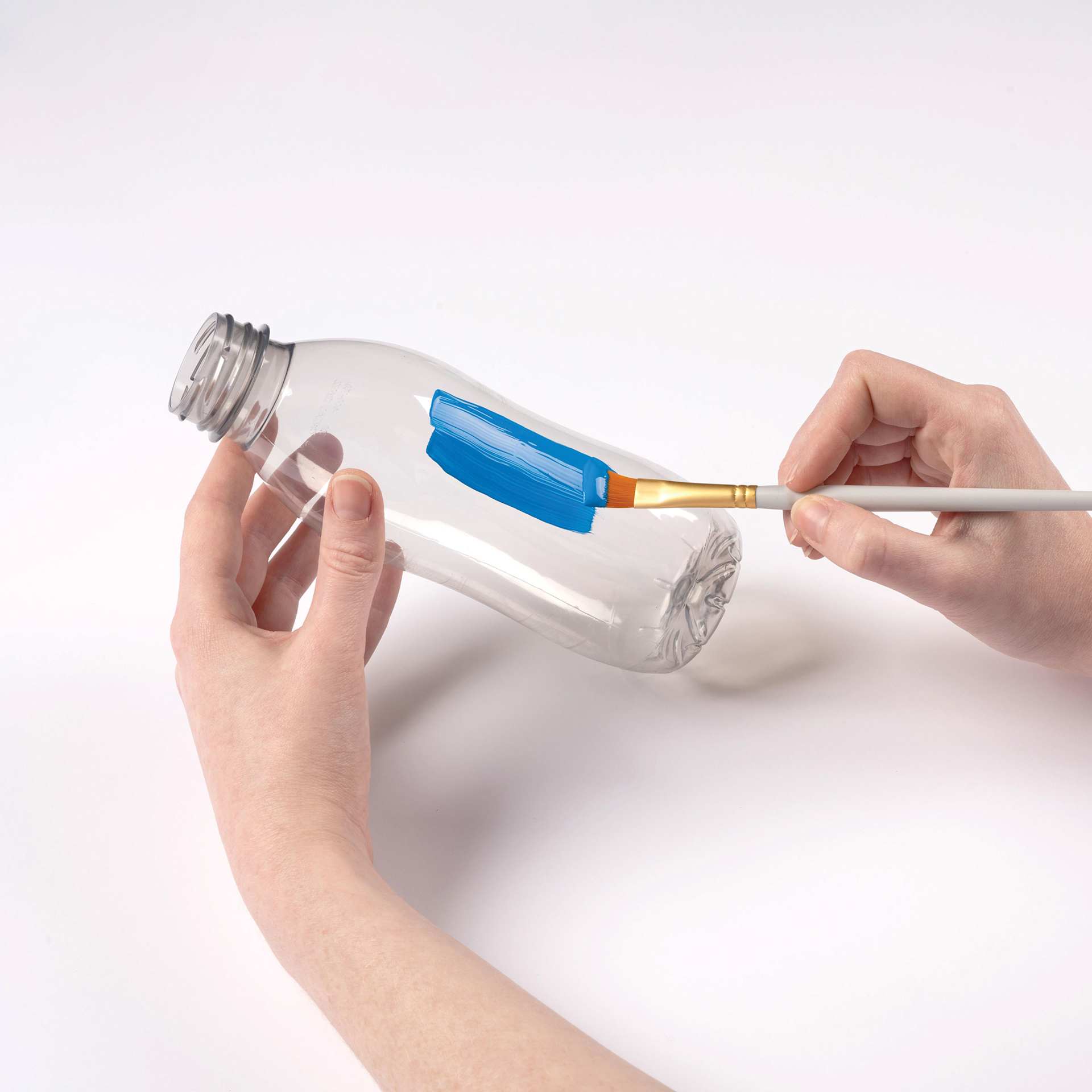 FolkArt Paints for Plastic being brushed on a plastic bottle.