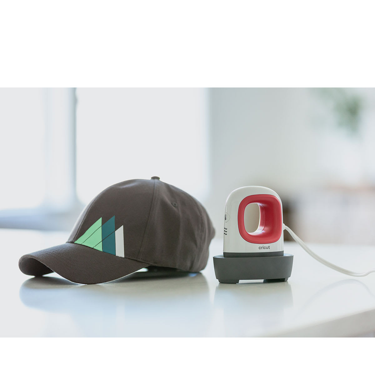 Cricut EasyPress Mini - Raspberry, next to finished design on Hat, not included.