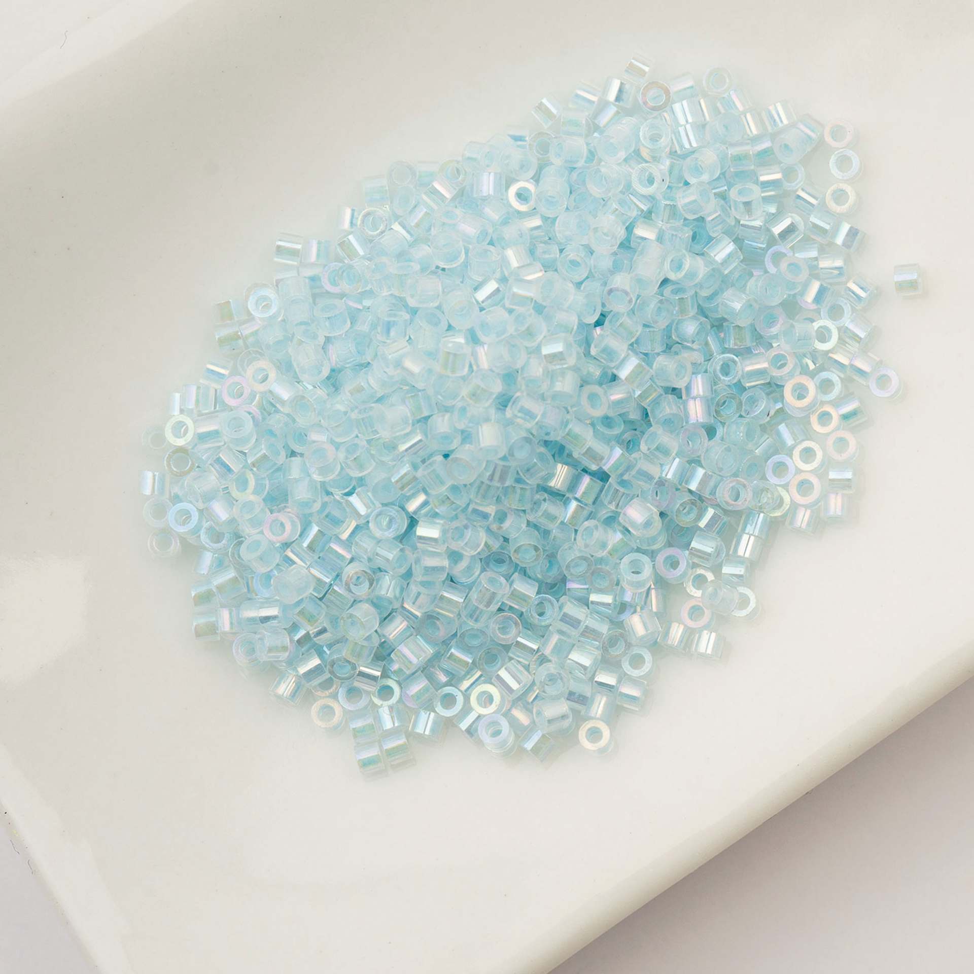 John Bead Cylin 11/0 Glow in the Dark Cylindrical Seed Beads - Sky AB, 25g sitting in dish