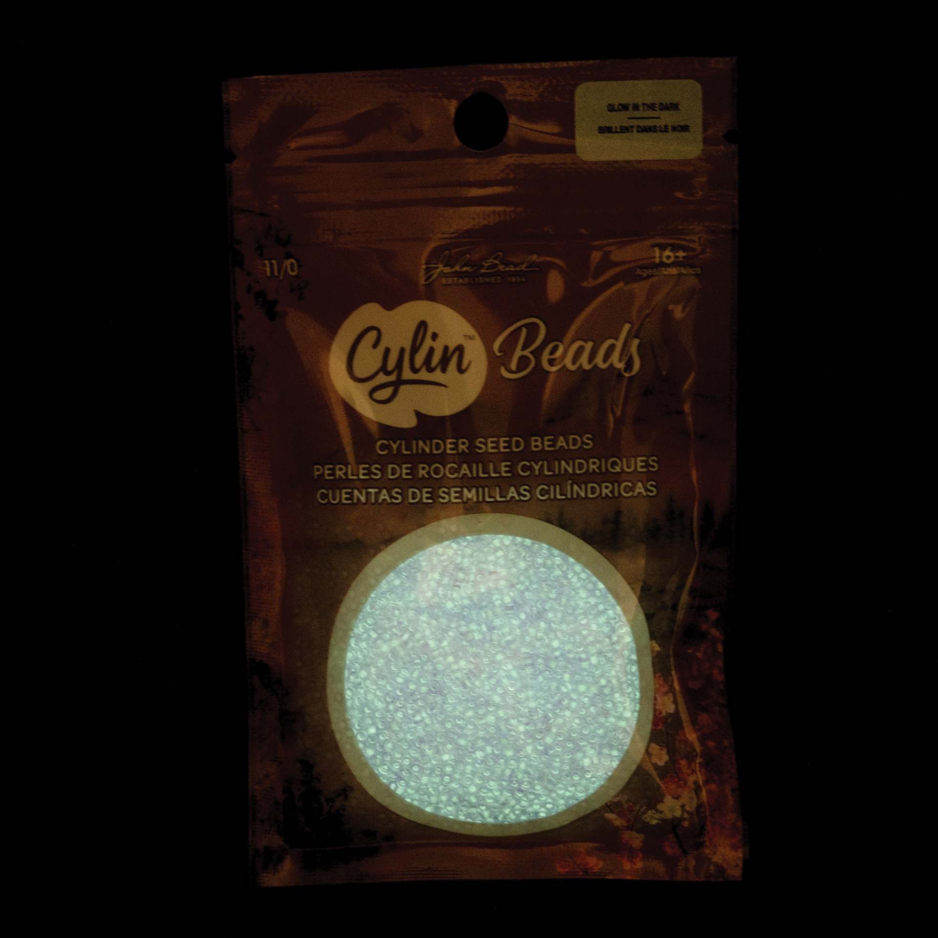 John Bead Cylin 11/0 Glow in the Dark Cylindrical Seed Beads - Purple, 25g front of packaging to show glow effect