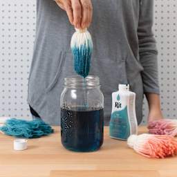 Rit All Purpose Liquid Dye - Teal, 8 oz, hand dipping pom poms in dyed water