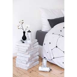 Nightstand made from books, painted with Montana Marble Effect Spray and shown in bedroom setting