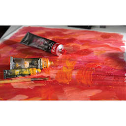 Three avaialble sizes of Maimeri Classico Oil Paints on a red and orange canvas.