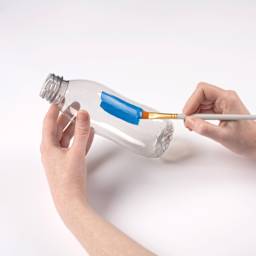 FolkArt Paints for Plastic being brushed on a plastic bottle.