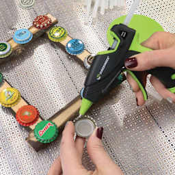 Surebonder Ultra Series Mini Dual Temp Glue Gun, in hand making a craft using bottle caps