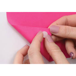 StikkiWorks StikkiDots Adhesive Wax Dots, hand placing dot behind paper