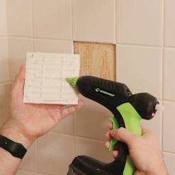 Surebonder Professional Battery Powered High Temp Glue Gun, in hand applying glue to ceramic tile