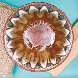 Amaco Potter's Choice Glaze - Ancient Copper applied to a dish in a flower pattern.