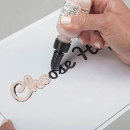 Liquid Sculpey - Transparent Amber, 1 oz (hand using the bottle to trace over letters)