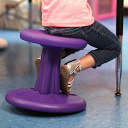 Child sitting on a purple Kore Design Kids Wobble Stool.