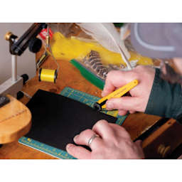 Olfa Quick-Change Rotary Cutter, in hand cutting paper on mat