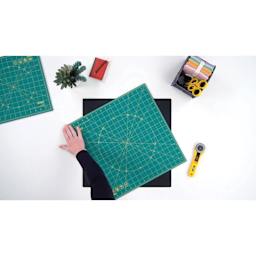 Olfa Rotating Cutting Mat - 12" x 12" - demonstration of the self-healing mat being rotated on the non-slipping mat
