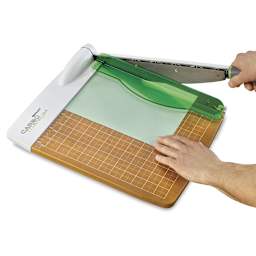 Westcott CarboTitanium Guillotine Paper Trimmer - Person cutting paper with trimmer
