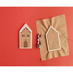 Rico Design Embroidery House Kit - Gingerbread House finished product next to in-process project