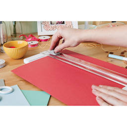 Cricut 12" Essential Tool Set - Hands shown cutting red paper with trimmer