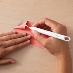 Cricut Everyday Iron-On Vinyl - Coral, tool in hand weeding the vinyl