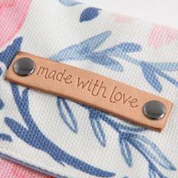 Dritz Double-Cap Rivets & Tools Set, example of two rivets inserted in leather tag