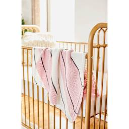 Lion Brand Feels Like Butta Yarn - Pink, blanket made of yarn hanging on baby crib