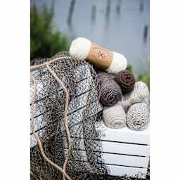 Lion Brand Fishermen's Wool Yarn collection of skeins on crate next to fishing net and lake