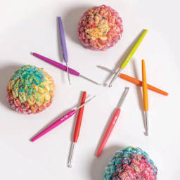 Prym Soft Grip Aluminum Crochet Hook Set - Set of 8, Sizes 2 - 6 mm scattered across table