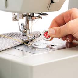 Singer Slant Tip Tweezers in hand removing thread from a sewing machine foot