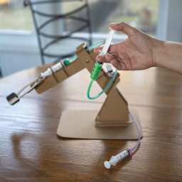 Kikkerland Newton’s Lab Make Your Own Hydraulic Claw Kit (Person pushing syringe to start hydraulic claw)