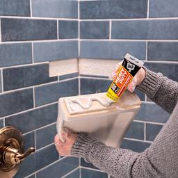 DAP Heavy Duty Instant Grab Adhesive - 3 oz Tube being applied to shower shelf