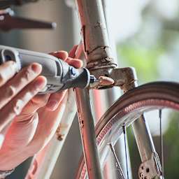 Dremel EZ Lock Accessory Kits - Hand using Sanding Accessory on Bicycle