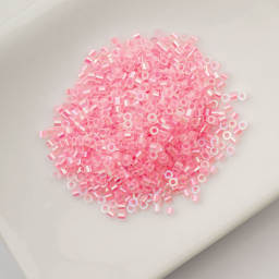 John Bead Cylin 11/0 Glow in the Dark Cylindrical Seed Beads - Rose AB, 25g sitting in dish