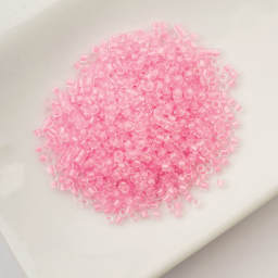 John Bead Cylin 11/0 Glow in the Dark Cylindrical Seed Beads - Pink, 25g sitting in dish