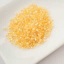 John Bead Cylin 11/0 Glow in the Dark Cylindrical Seed Beads - Gold Yellow AB, 25g sitting in dish