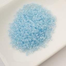 John Bead Cylin 11/0 Glow in the Dark Cylindrical Seed Beads - Blue, 25g sitting in dish