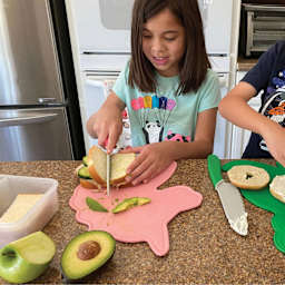 Handstand Kitchen Cutting Board & Knife Set, sandwich being cut on top of Unicorn cutting board.