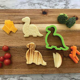 Handstand Kitchen Sandwich Cutter Lunch Set - Dinosaur, cut outs of bread on cutting board. 
