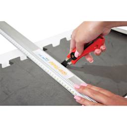 Logan Cos-Tools Knife, in hand cutting through foam board with straight edge (not included)