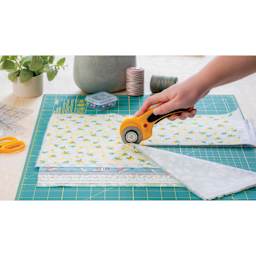 Olfa Ergonomic Rotary Cutter, in hand cutting multiple layers of fabric