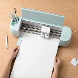 Cricut Smart Label Dissolvable Paper, hand feeding sheet through the machine (not included)