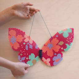 Perler Bead D.I.Y. Butterfly Activity Kit preparing to hang finished butterfly on wall