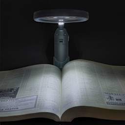 Carson MagniLamp LED Magnifier over open book in dark space