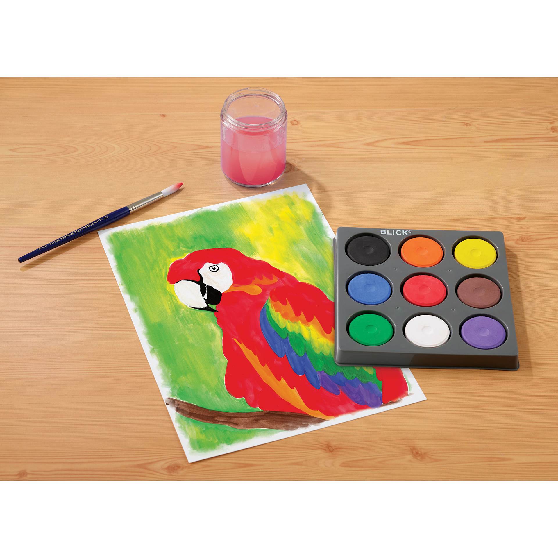 Blick Essentials Tempera Cakes Set of 9 Classic Colors in a tray, with brushes, a water cup, and a painting of a parrot.