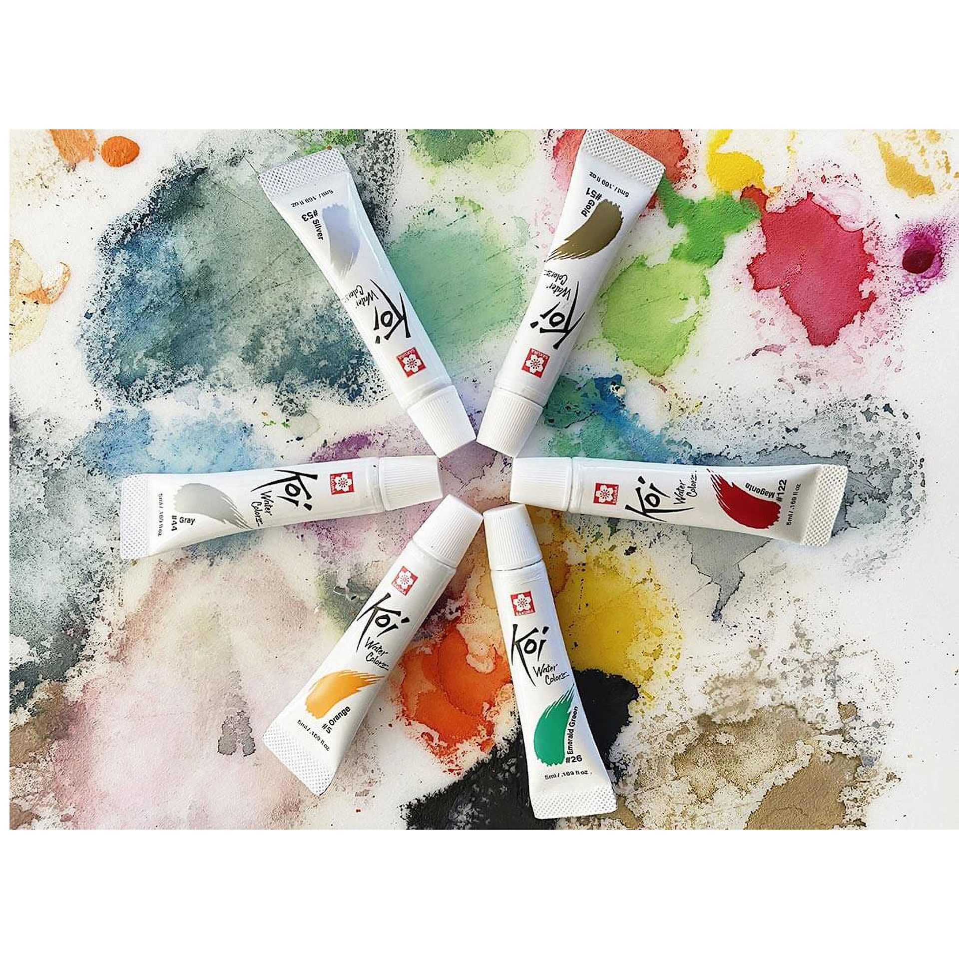 Sakura Koi Watercolor Tubes arranged in a circle on a paint splattered background. Sakura Koi Watercolor Tubes arranged in a circle on a paint splattered background.