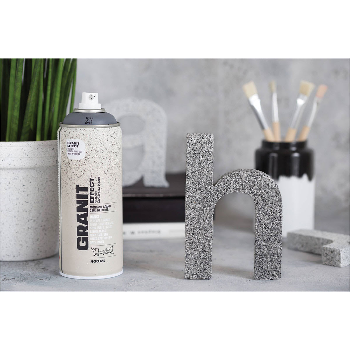 Montana Granit Effect Spray - Spray can on desk next to painted standing 3D letters Montana Granit Effect Spray - Spray can on desk next to painted standing 3D letters