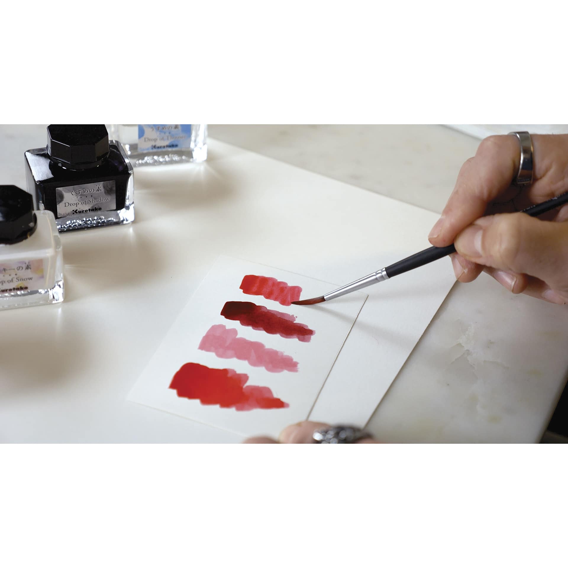 Kuretake Ink-Café Drop of Thinner, brush in hand creating swatch