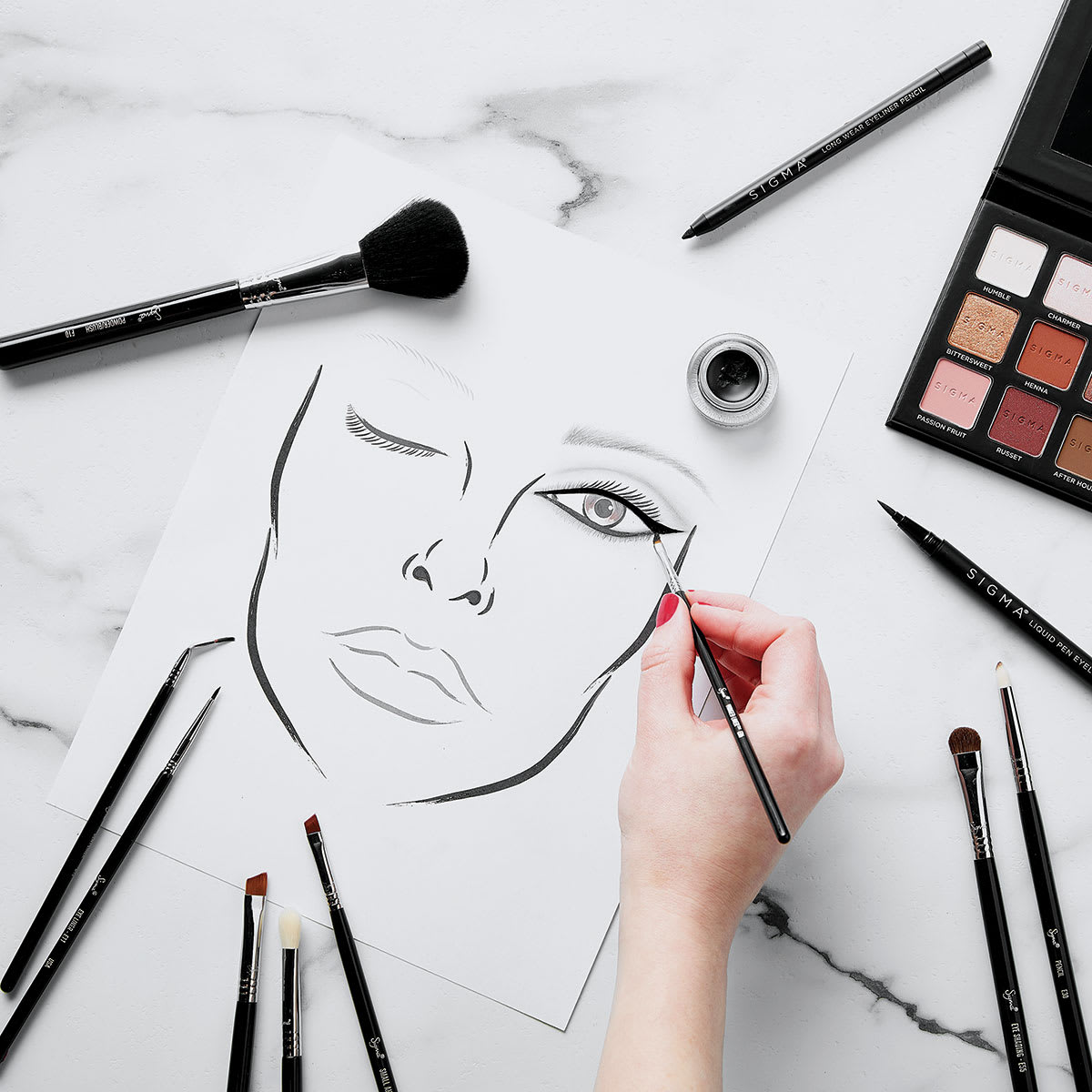 Sigma Beauty Brushes - Scattered brushes shown with makeup and face sketch