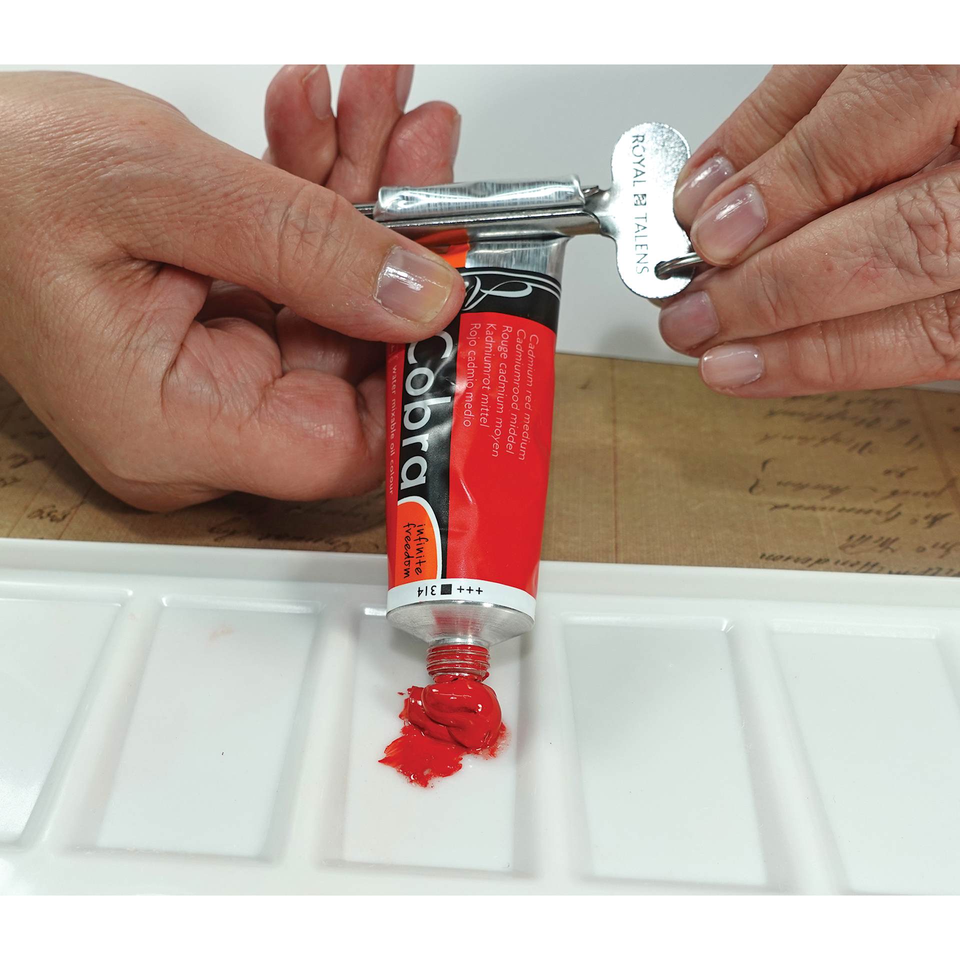 Royal Talens Tube Wringer being used on a tube of red paint