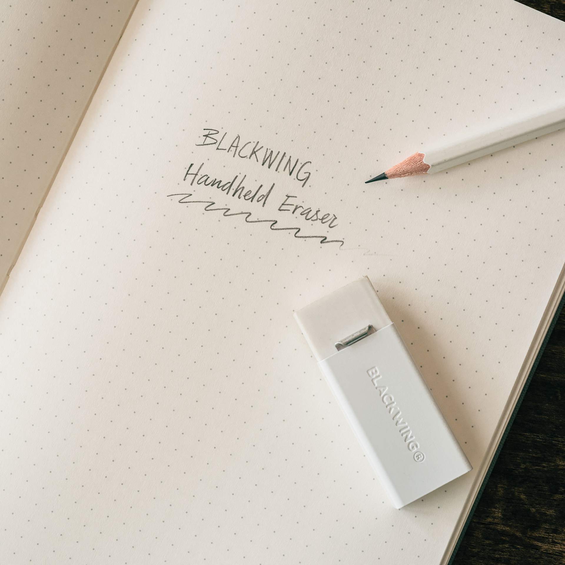 Blackwing Handheld Eraser with White Holder, on top of paper next to pencil (non included)